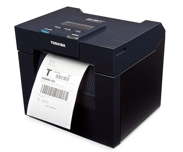 Imprimante d'étiquettes TOSHIBA TEC DB-EA4D délivrant une étiquette code-barres, vue trois quarts