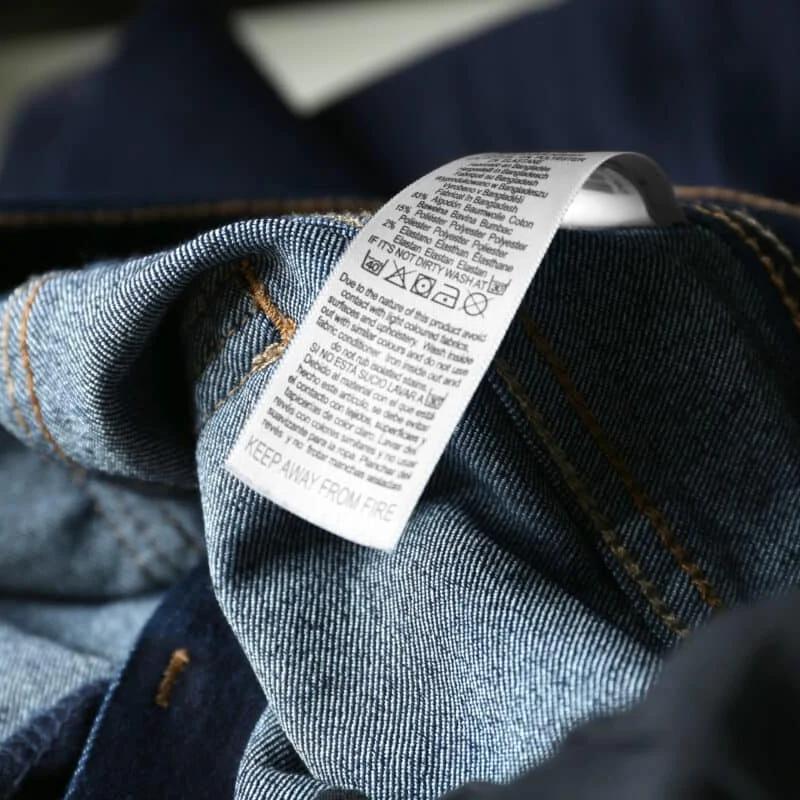 Étiquette d'entretien textile imprimée en transfert thermique, cousue dans un jean